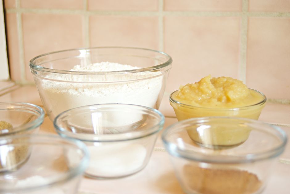 Close-up of glass bowls with flour, applesauce, and sugar, ready for baking.